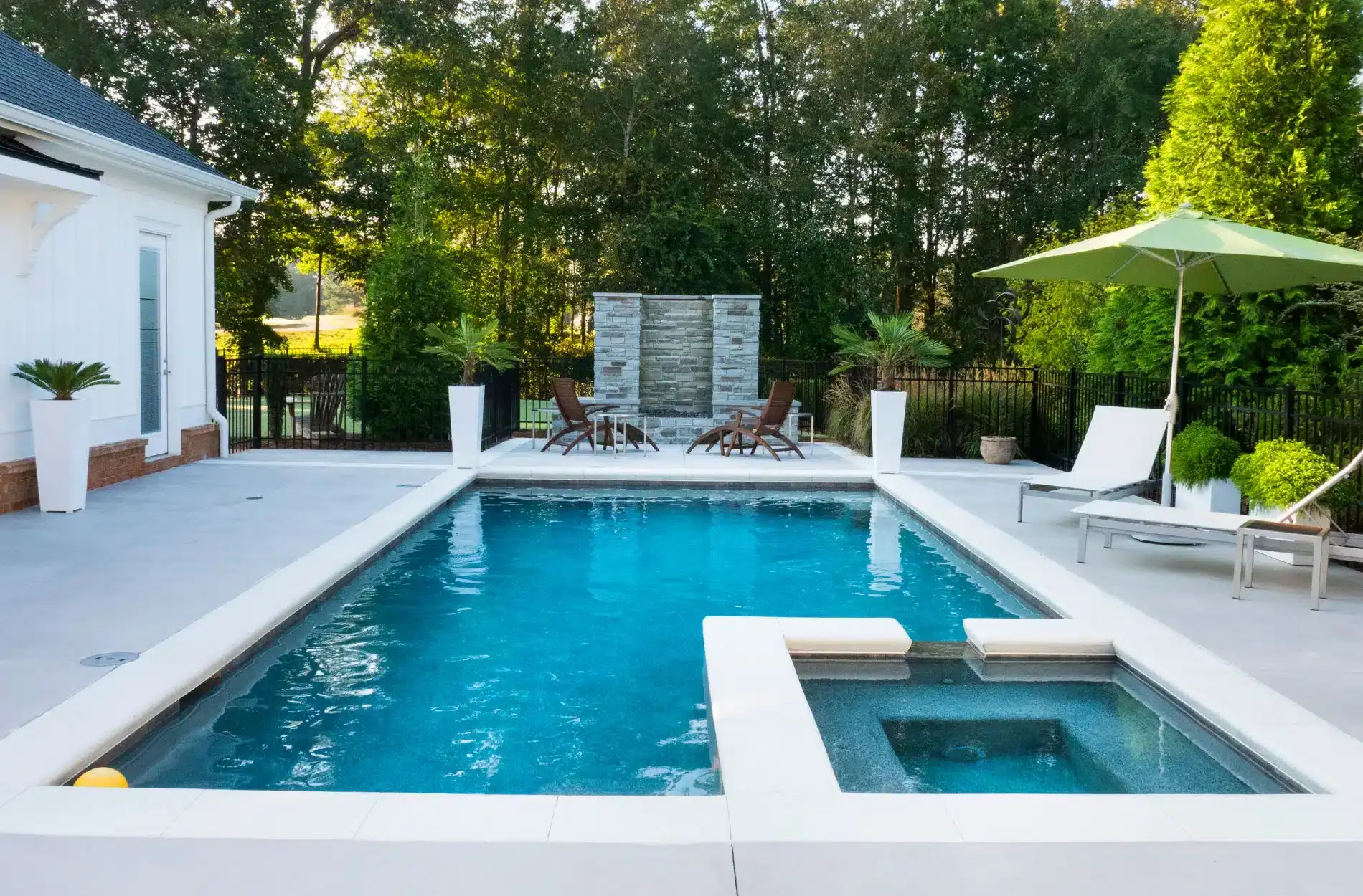 Custom pool with raised spillover and lush landscaping